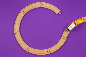 Obraz premium Toy train and wooden rails on purple violet background