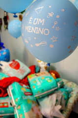 blue balloons written its a boy in portuguese language