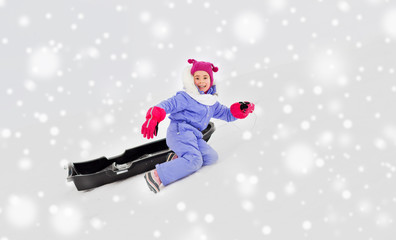 Fototapeta na wymiar childhood, sledging and season concept - happy little girl with sled on snow hill in winter