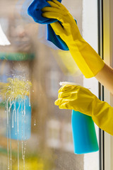 Gloved hand cleaning window rag and spray