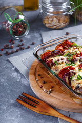 Chicken Casserole of Tomatoes, Onions, Cheese and Spices Menu and Restaurant Concept On Gray Background On the Kitchen Table with Dining Accessories