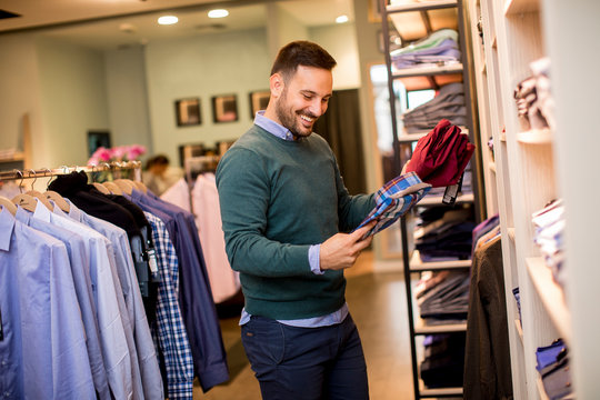 Portrait Of A Young Man Looking At Clothes To Buy At Shop