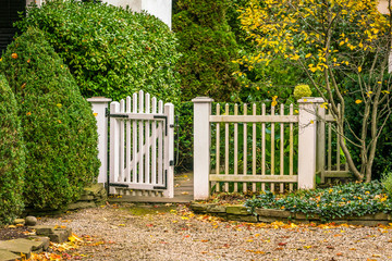 Vintage garden gate with white picket fence, inviting, open, with pebble stone walkway. Background, concept.