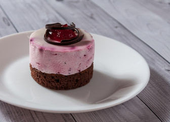 Fresh cherry cake round shape on a light wooden background. Biscuit cake on a wooden table