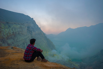 Fototapeta premium Young man sitting on top of mountain and looking view of sunrise over the lake.
