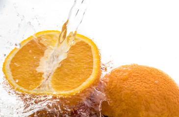 Two halves of juicy orange close up with a splash of water on them and flying water above