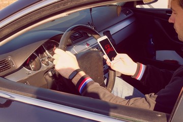 A IRRESPONSIBLE man driving a car with a MOBILE PHONE in his hand.A man holds a driving wheel and a...