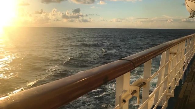 View standing by railing of cruise ship deep blue ocean beautiful sunset oceanic horizon panning to water surface 26 second footage