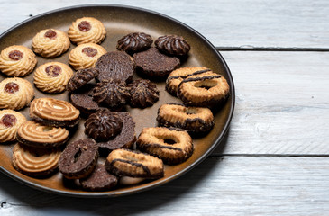 shortbread butter cookies with chocolate and plum jam on a white wooden table