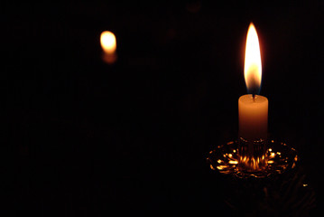Kerze mit Flamme vor schwarzem Hintergrund