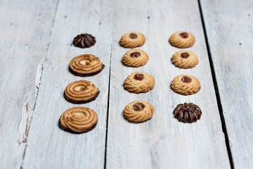 shortbread butter cookies with chocolate and plum jam on a white wooden table