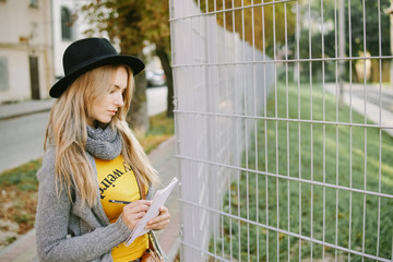 Girl in hat posing on camera. Rain in the autumn park.