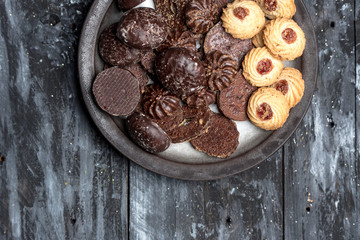 shortbread butter cookies with chocolate and plum jam on dark wooden table