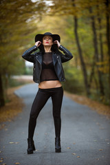 Young woman posing a an autumn day on a road in the woods.