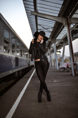 Obraz premium Young sexy woman dressed in black posing on a train station pier.