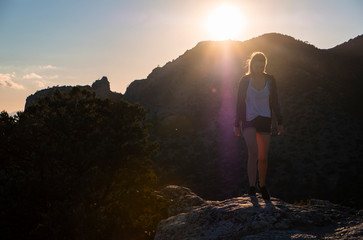 Girl in the mountains on top at sunset or dawn