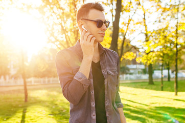 a man a man dressed in stylish clothes, listening to music through wireless headphones and walking...