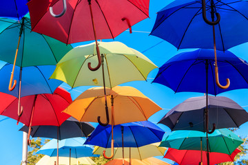 Obraz premium Multicolored umbrellas on the city street. The city street is decorated with many colorful open umbrellas