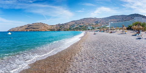 Sunbeds and umbrellas on Vlycha beach near hotel resort (Rhodes, Greece)