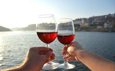 Wine glasses in the hands against Douro river in Porto, Portugal