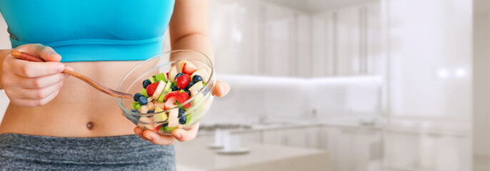 Young woman eating a healthy fruit salad after workout. Fitness and healthy lifestyle concept.