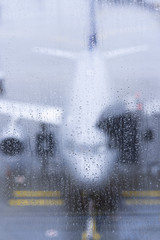 Unfocused airplane view through wet glass raindrops closeup boarding 