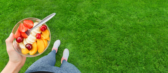 Naklejka premium Young girl eating a fruit salad after a workout . Fitness and healthy lifestyle concept.