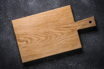 Empty wooden cutting board on black stone table.