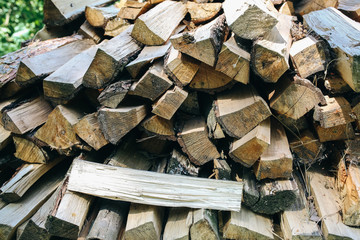 Natural firewood lying in a pile outdoors. Wood background texture. Eco friendly wallpaper.
