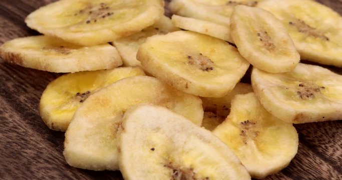 Dried banana chips rotate on wooden plate