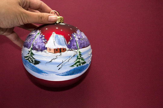 Christmas tree toy ball in bordo cherry color isolated on bordo and white background. Winter drawning landscape. House in snow forest. Christmas decoration. Colorful christmas and new year concept.