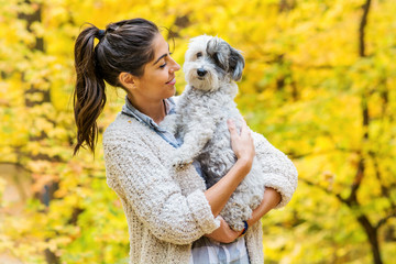 Beautiful Smiling Woman Hugging  Her Cute Havanese Dog in the  Autumn Yellow Forest.Owner and Dog Happy Together 