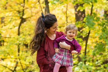 Happy Mother Hugging  her Baby Girl in the Autumn Park .Mother and Daughter .Happy Family, Mother with Little Child in the Nature