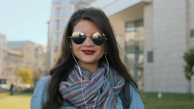 Portrait of cute girl in headphones, listening to music outdoor.