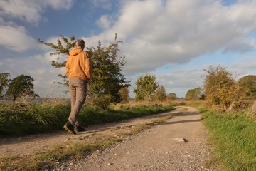 Mann wandert alleine auf einem Feldweg in idyllischer Landschaft