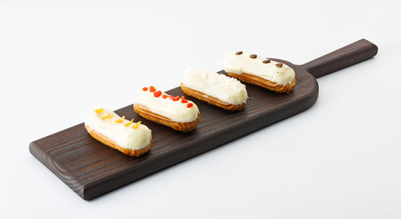 four eclair cakes on wooden board isolated on white background
