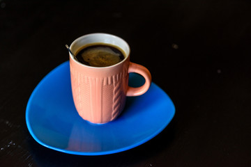 A cup of coffee on a blue plate.