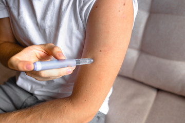 close up of handsome stylish young teen caucasian with syringe inject insulin to his shoulder...