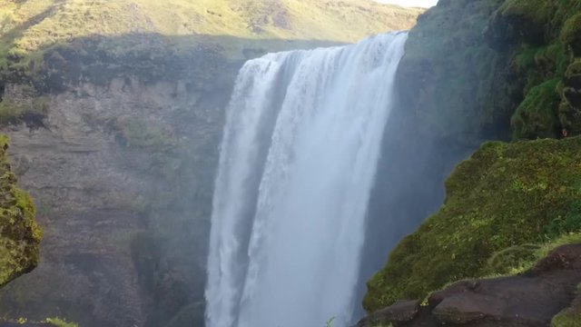 Aerial drone shot flying over the famous Skogafoss waterfall in Iceland. Slow motion sunny day. low altitude flight.