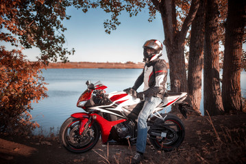 biker in a helmet sitting on a sports bike near the lake