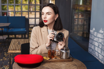 Young beautiful woman with a camera drinking tea in a cafe