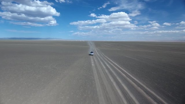 Aerial drone shot of a van riding in desert zoom out