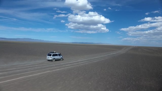 Aerial drone shot following a van in the desert Mongolia