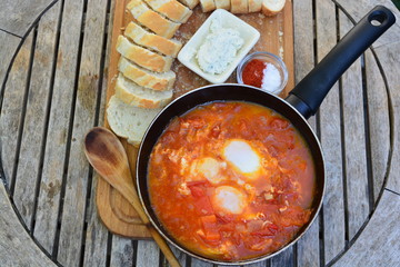 Shakshuka in a pan on a wooden board