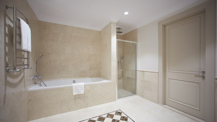 Nice bathroom in a modern style with gray tiled walls. There is a white bath with a glass...