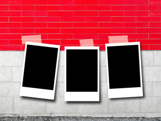 Three blank rectangular instant photo frames on red and white stone brick wall background