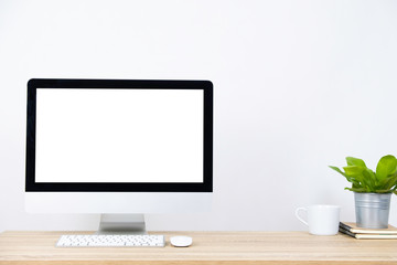Modern PC Monitor and white screen, mouse, keyboard and some stuff on the wooden table. White background and copy space. Business or Work space theme