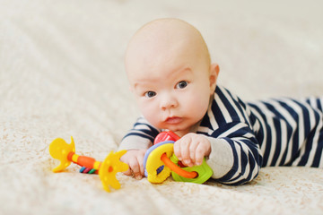 funny baby lying in the bed with toys