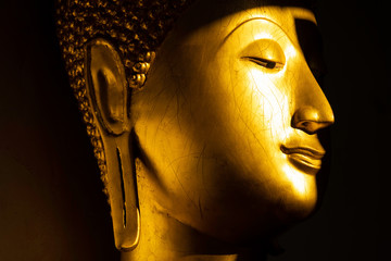 close up face of golden buddha statue in the light and shadow of sun at Wat Pra Sri Mahathat temple, Phitsanulok province, Thailand