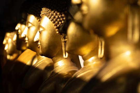 close up row of golden buddha statue in the light and shadow of sun at Wat Pra Sri Mahathat temple, Phitsanulok province, Thailand